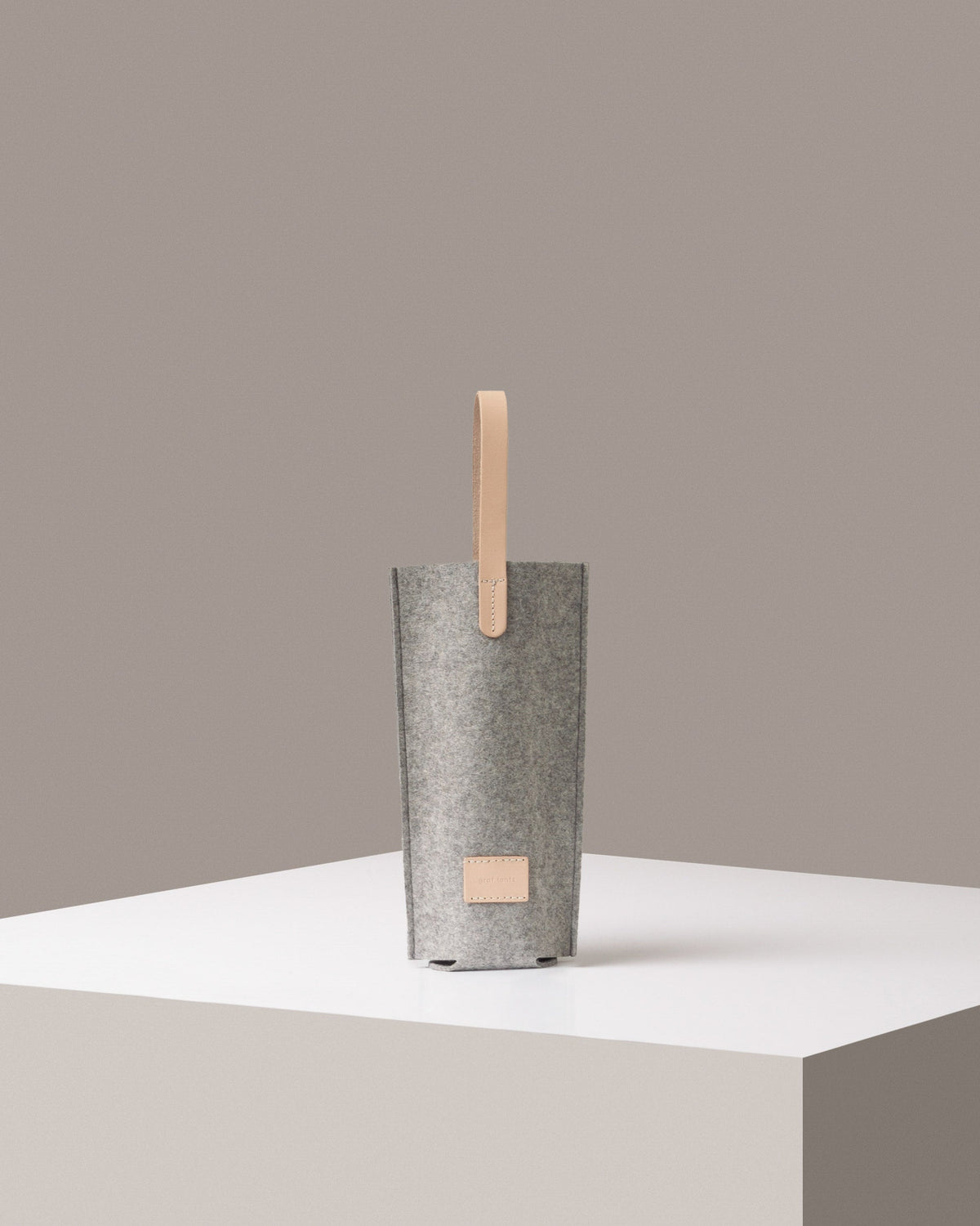 A Hana Merino Wool Bottle Bag light grey standig on a white base, front view
