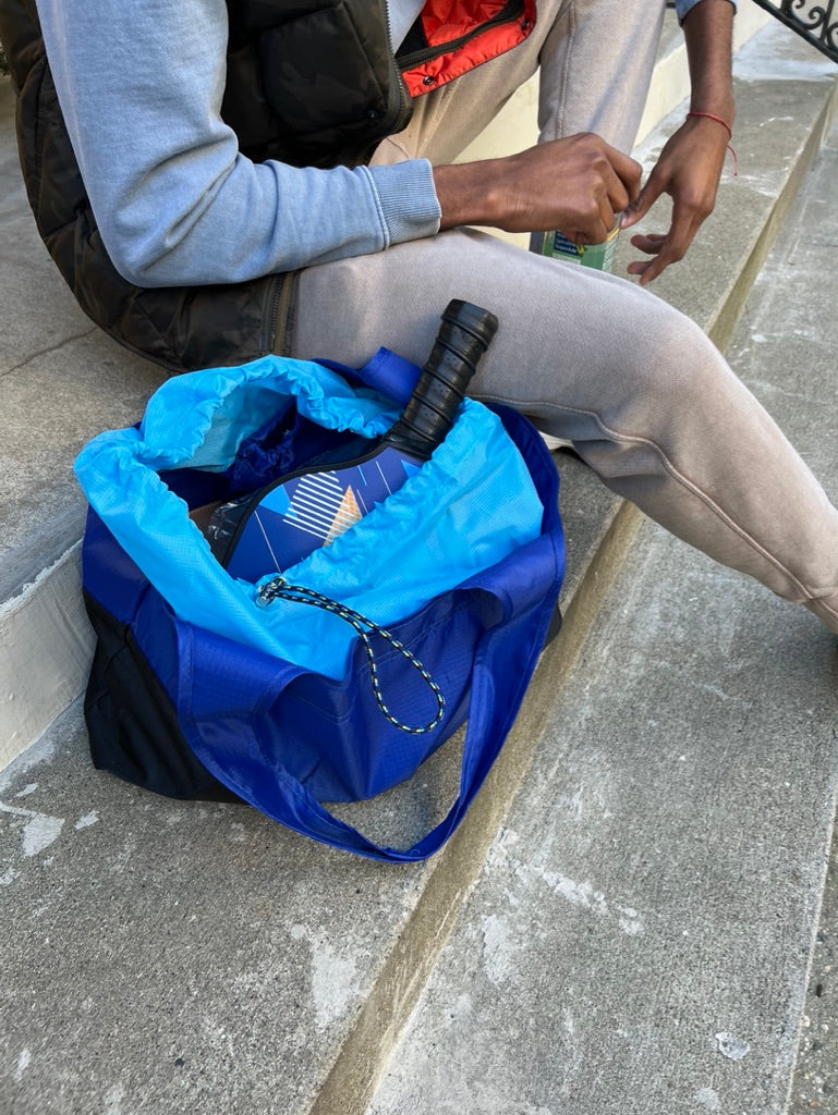 man on stairs with deep blue bag at their side containing sports paddles