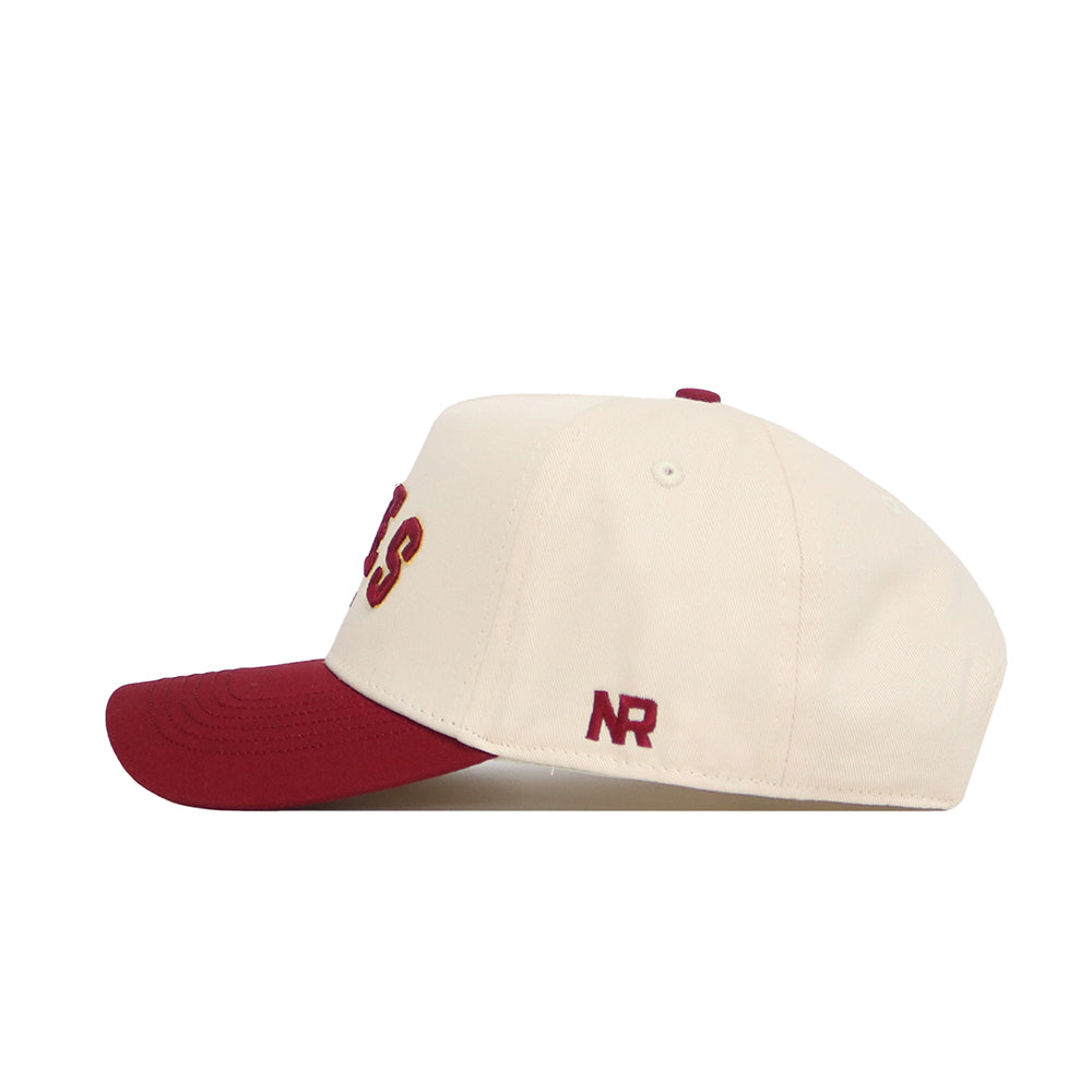The Ames Hometown Hat by No Rivals is a cream snapback with a red brim, red embroidered NR on the side, partial letters on the front, and is made from high-quality cotton for a comfortable, structured fit.