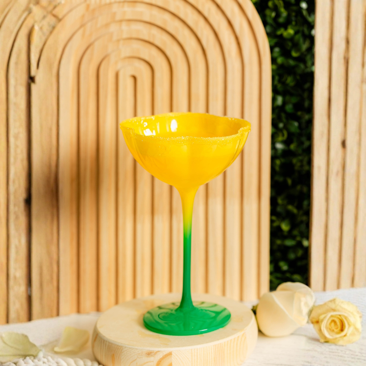 Yellow and green glass vase on a wooden surface with a blurred natural background