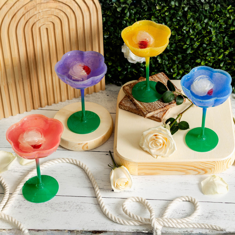 Colorful flower-shaped drink holders on a wooden surface with a floral background.
