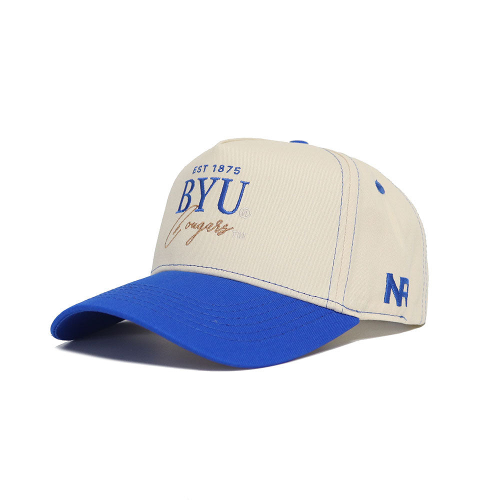 The BYU Vintage Hat by No Rivals features a beige crown, blue bill and stitching, “EST 1875 BYU Cougars” on the front, and an N/A logo on the side. Made from high-quality cotton.