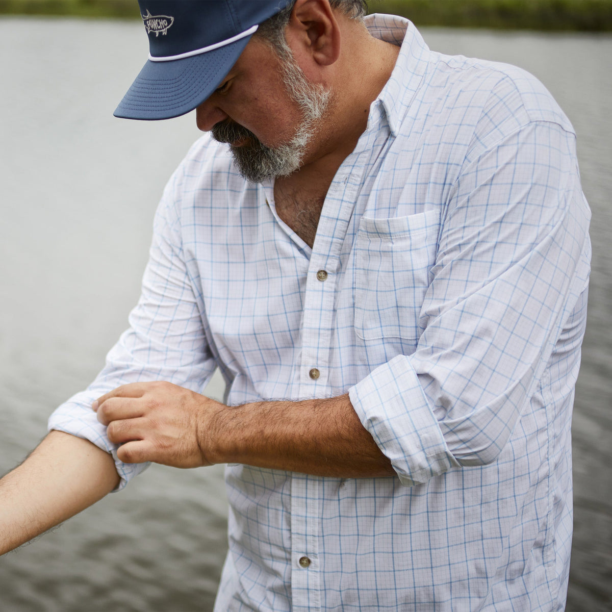 man with blue grid long sleeve button down rolling up sleeve 