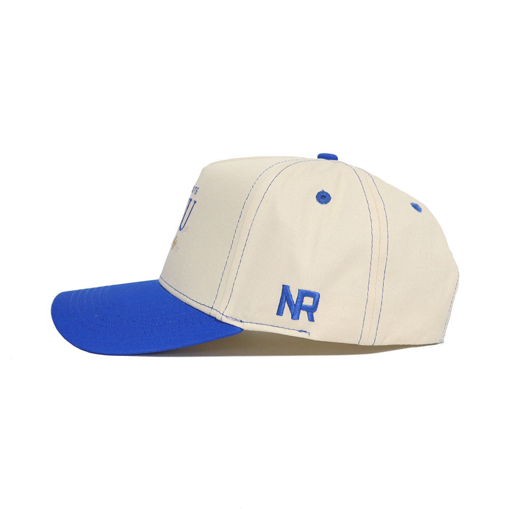 The BYU Vintage Hat by No Rivals is a beige snapback with a blue brim, button, and stitching. Made from high-quality cotton, it features the embroidered blue initials NR on the side for a stylish finish.