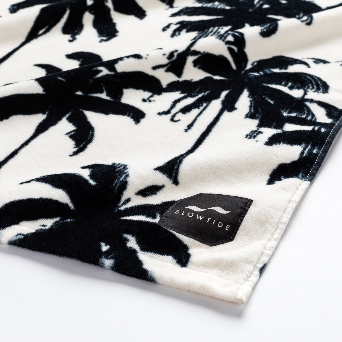 Beach towel, absorbent fabric with black palm tree pattern on white.