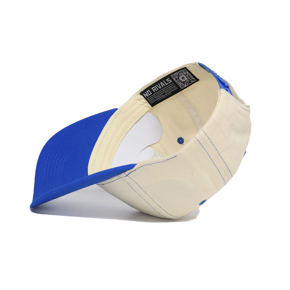 The BYU Vintage Hat by No Rivals is a blue and cream snapback shown upside down, revealing its interior stitching, gray sweatband, and label with text plus a QR code. Made from high-quality cotton for comfort and durability.