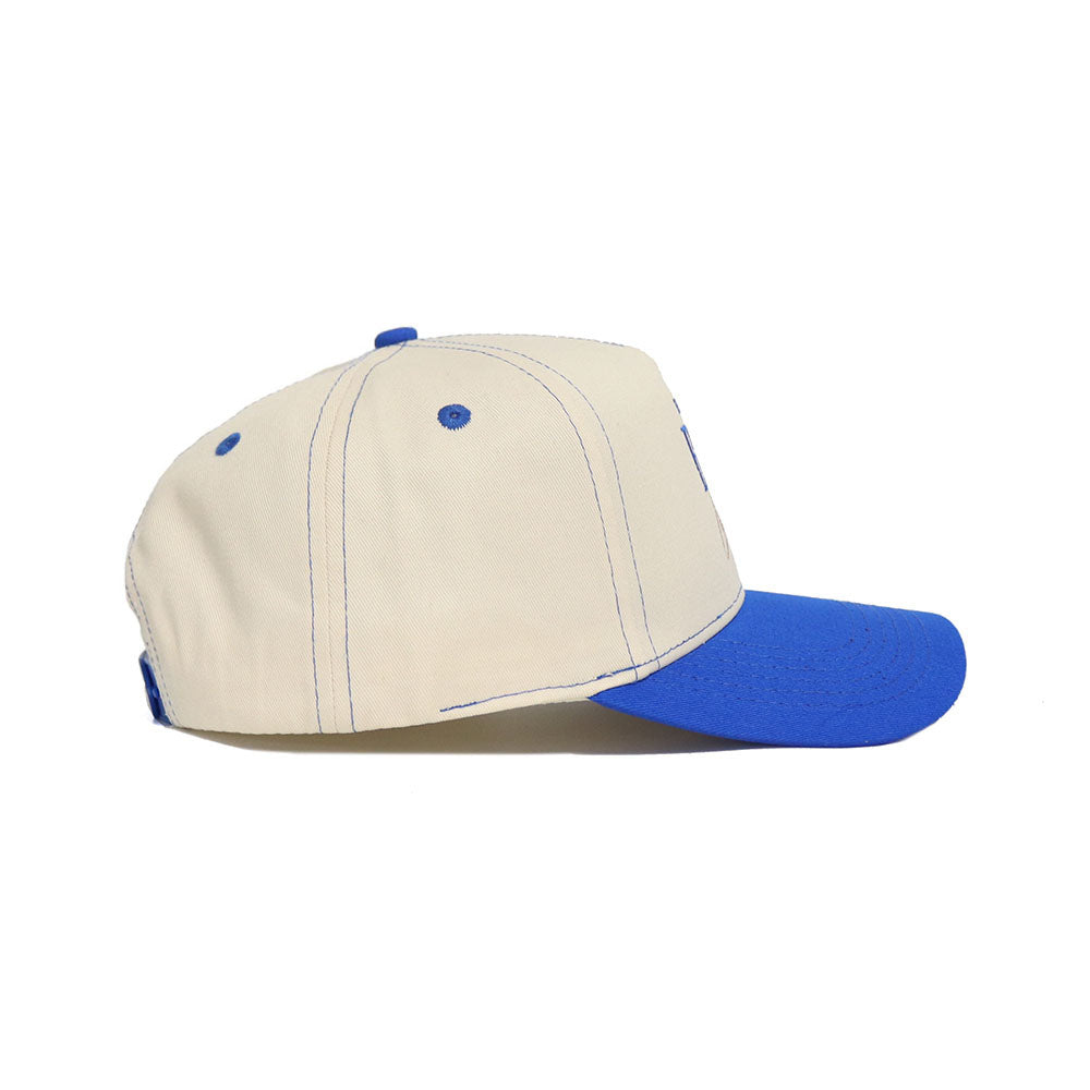 The No Rivals BYU Vintage Hat is a beige snapback made of high-quality cotton, featuring blue stitching, blue ventilation eyelets, and a blue curved brim, shown in side view on a white background.