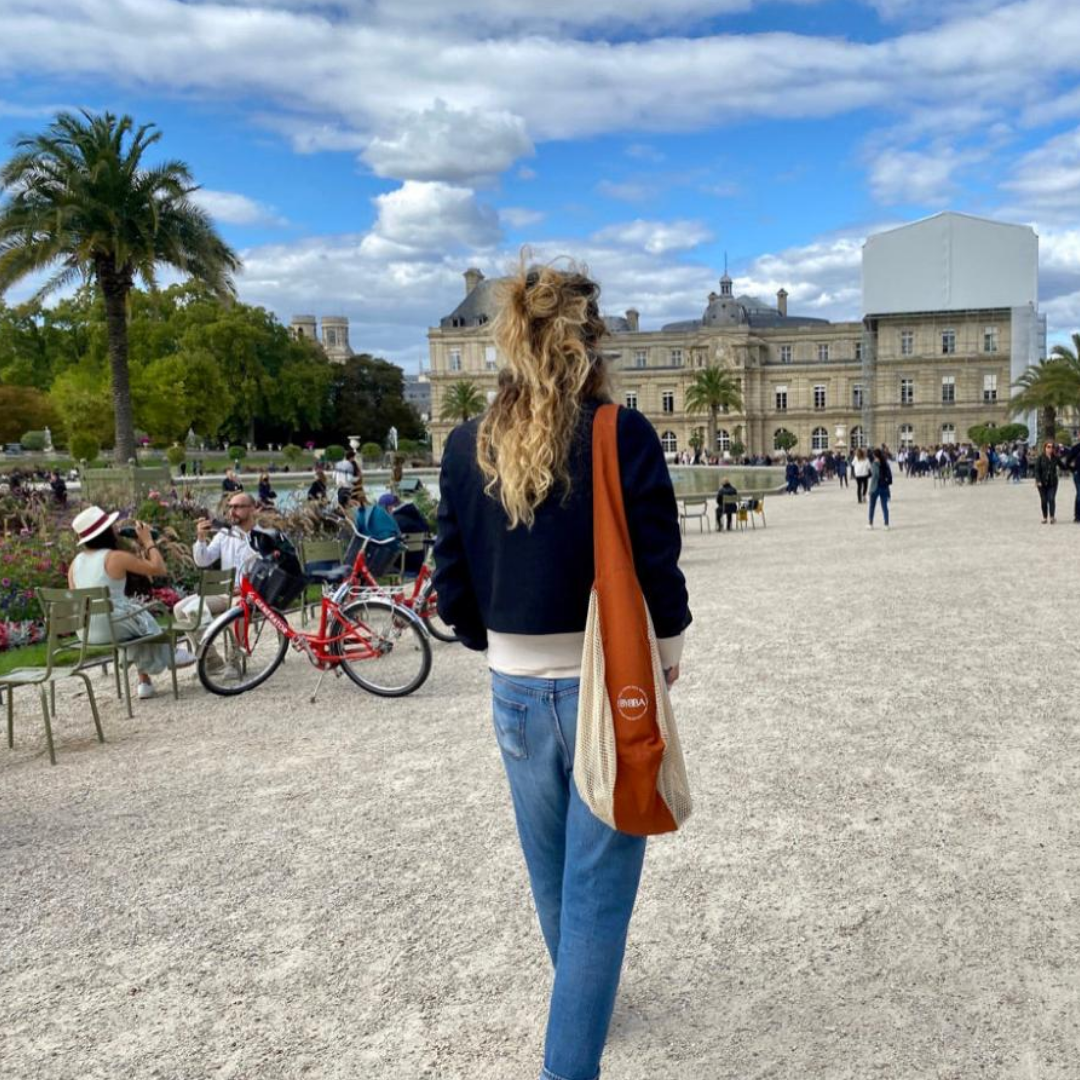 Packable, foldable, reusable tote made from recycled ocean plastic, carried in Paris park