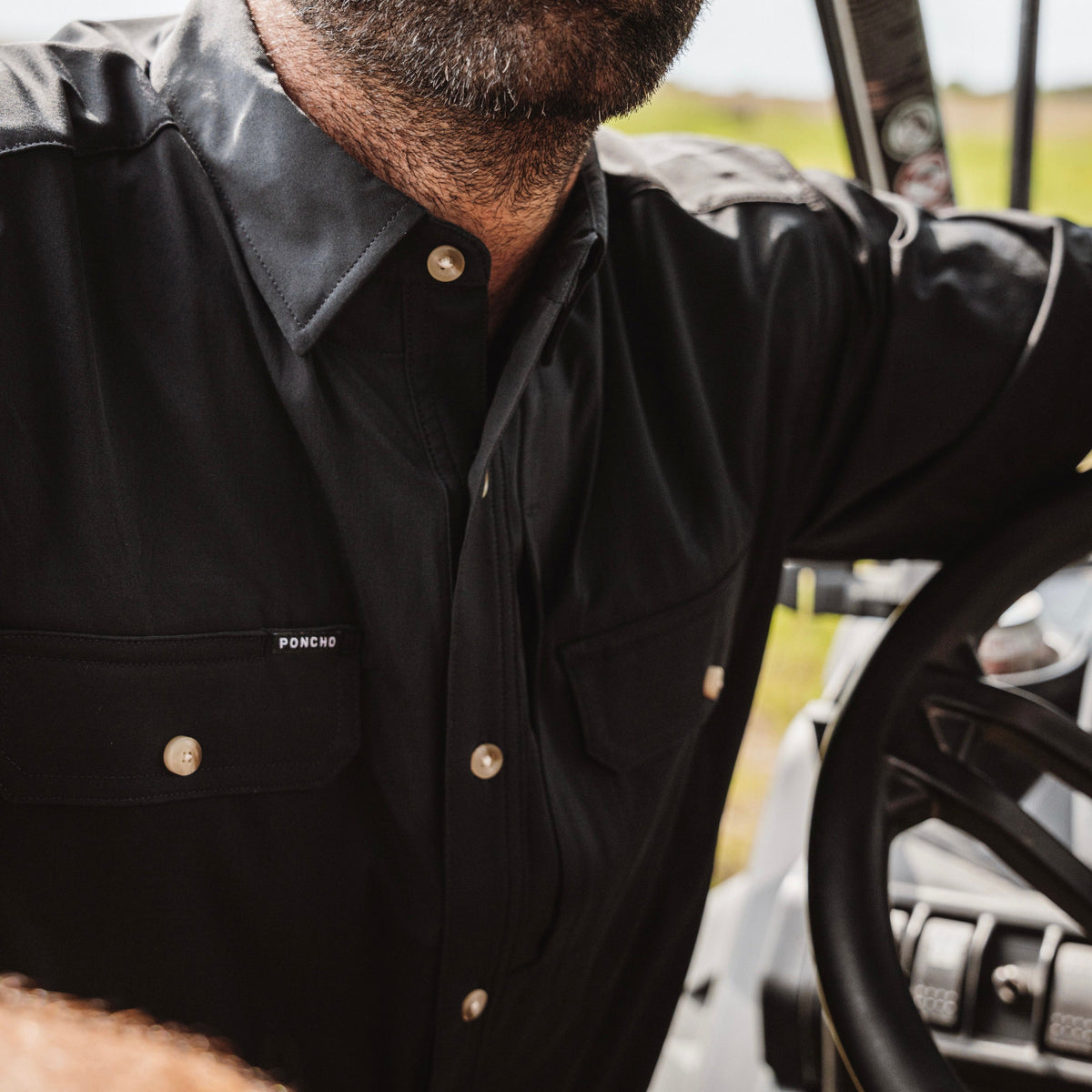 Close up photo of man&#39;s chest area highlighting a black short sleeve performance fishing shirt