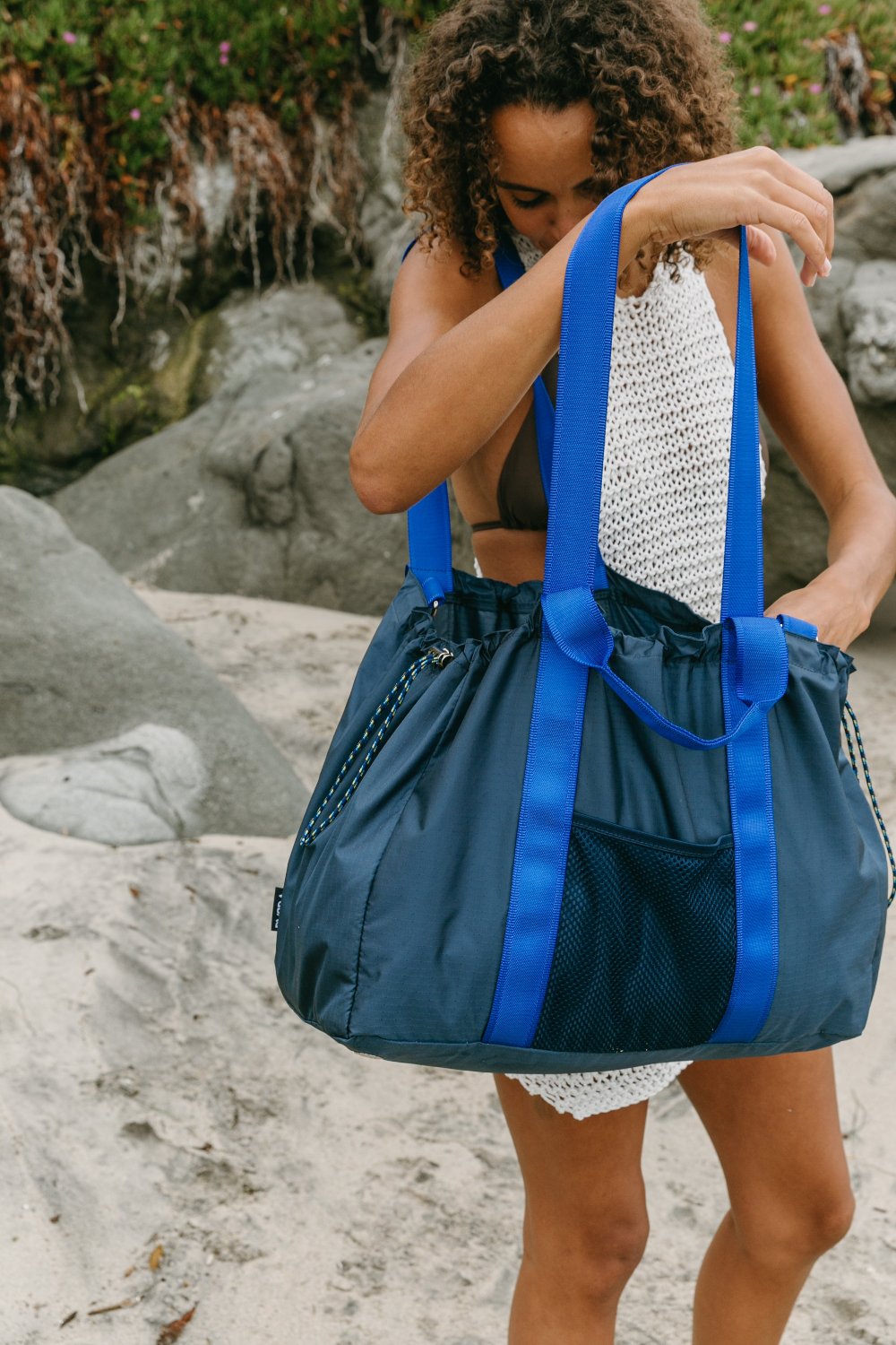 Girl holds open navy duffle tote while rummaging through it