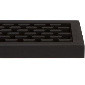 Close-up of a black silicone bar mat with a grid of raised drainage nubs.