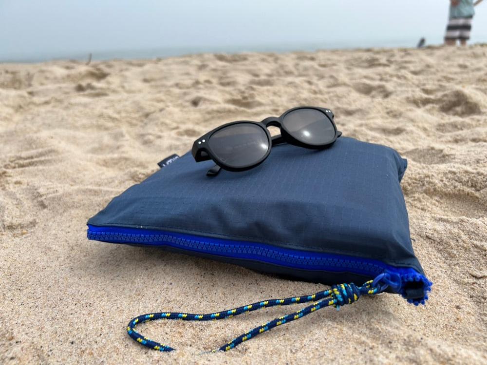 navy pouch at the beach with sunglasses