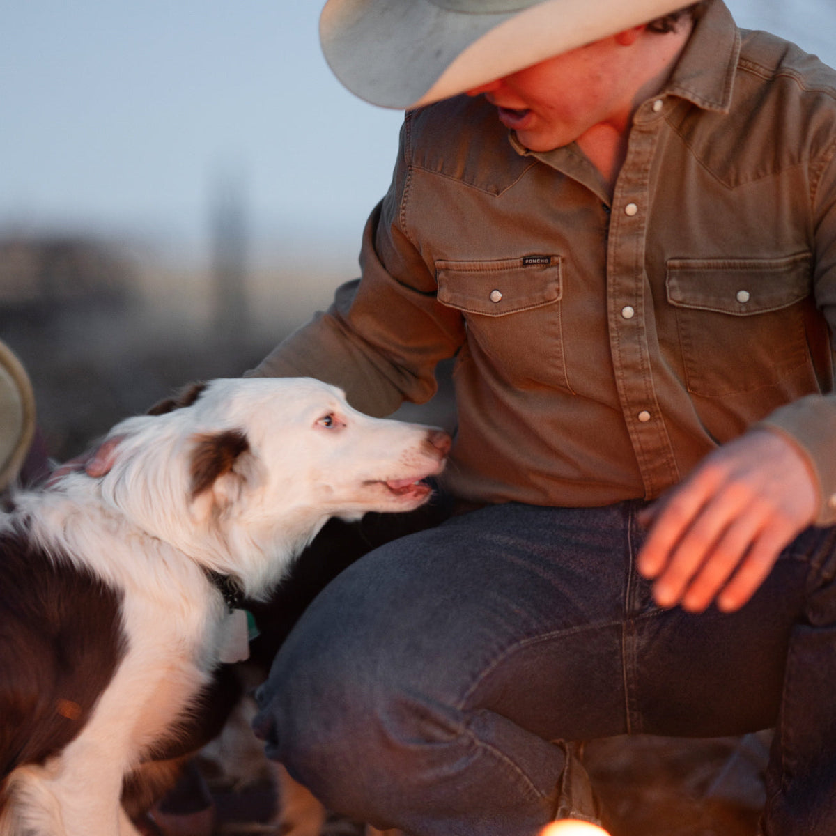 Man petting dog in brown denim shirt 