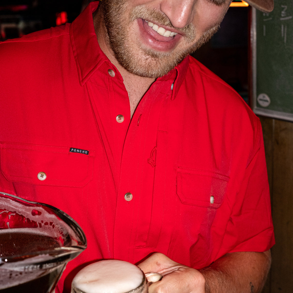 man pouring beer wearing red short sleeve shirt