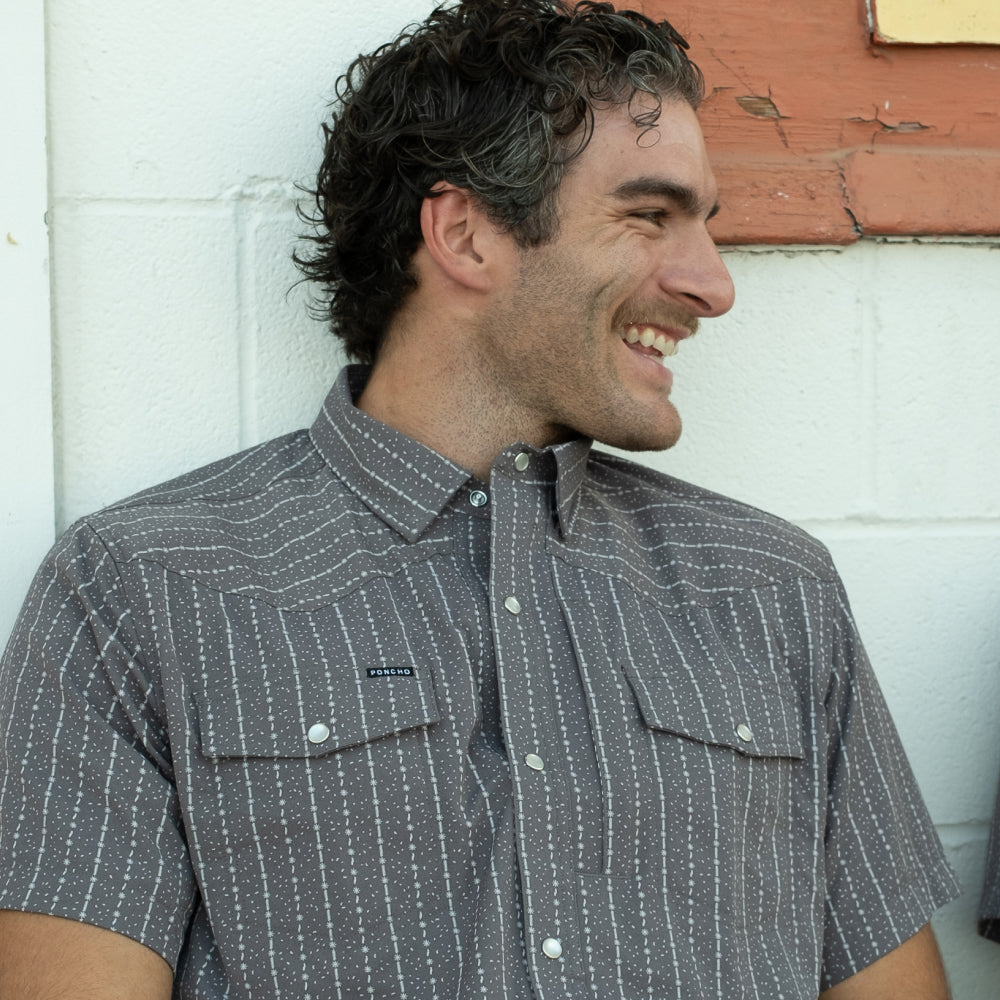 man smiling wearing grey and white short sleeve shirt