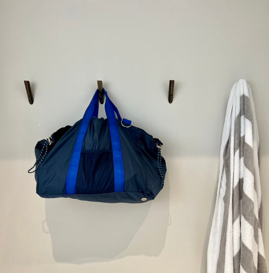 navy duffle hanging on a peg on a wall