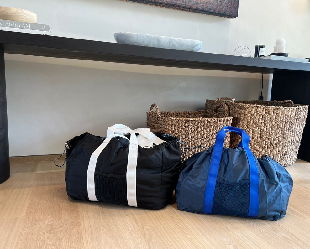 black and navy bags on the floor by baskets and a bench