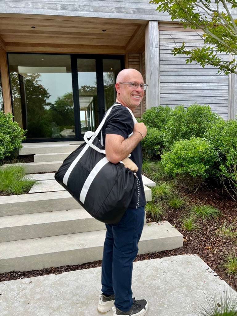 man holding large black bag outside of building
