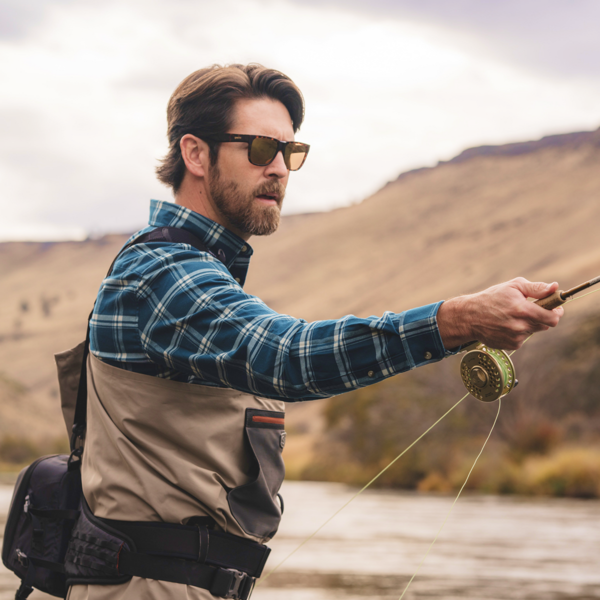 man holding fly rod wearing the deschutes flannel