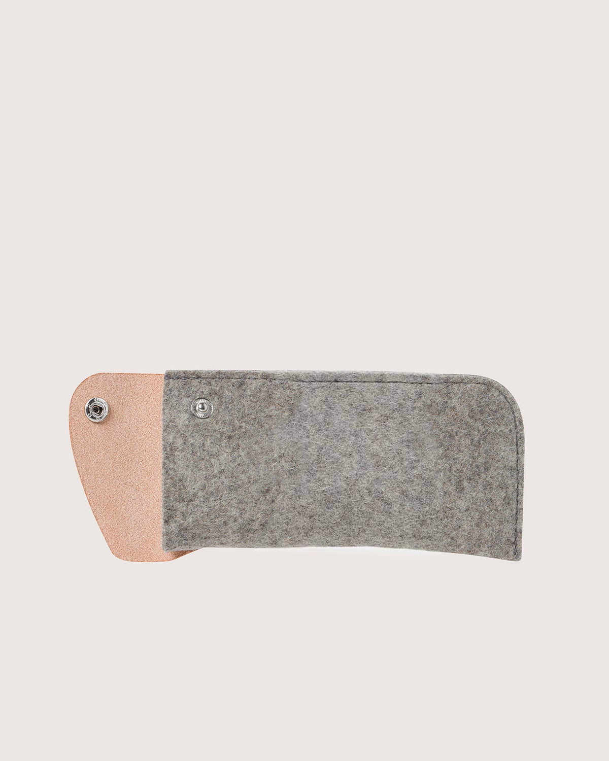 Graf Lantz offers a stylish eyeglass sleeve designed in gray Merino wool felt with a pink leather flap, secured by a snap button. Its minimalist design elegantly lies flat against a neutral background.