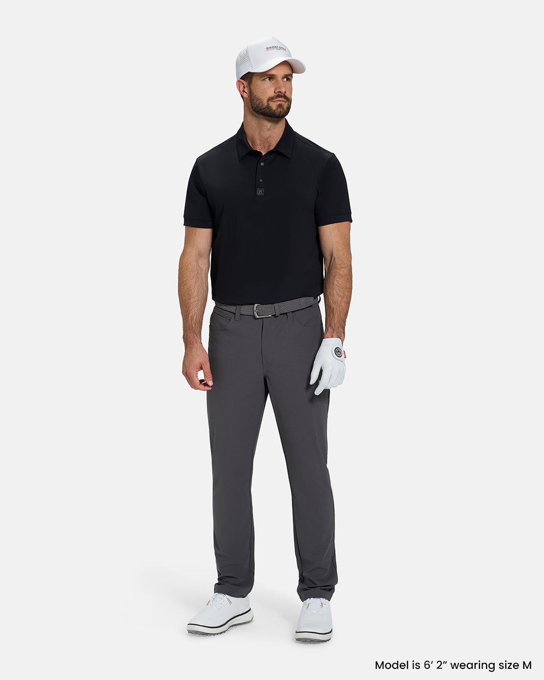 Full Body View of Black Ghost Golf Core Polo Tucked on White Male Model wearing grey pants white gloves grey belt white shoes and white hat #color_black