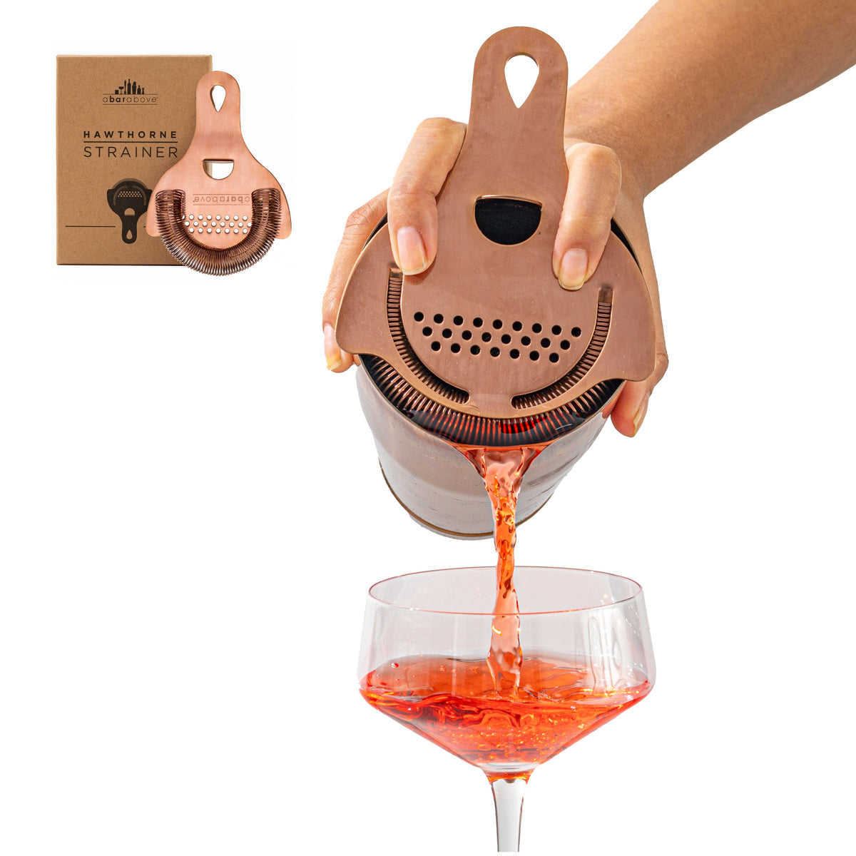 An antique copper Hawthorne strainer actively pouring a red cocktail, beside its branded product box.