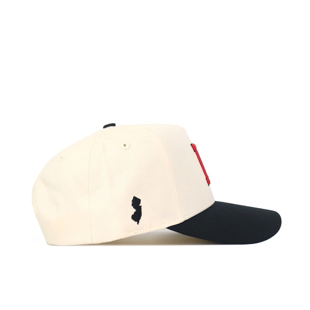 The No Rivals Classic Rutgers Hat (B2B) features a cream crown, black brim, and a small black New Jersey patch on the side. Made from high quality cotton with an adjustable snapback for comfort.
