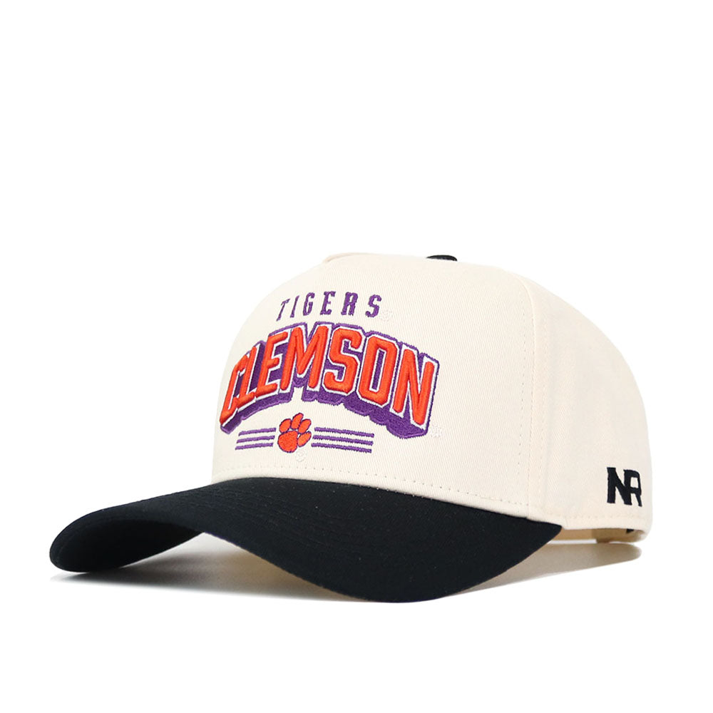 The Clemson Letterman Hat by No Rivals is a cream cotton baseball cap with a black brim, orange and purple "Clemson" lettering, "Tigers" above, a small paw print below, and a black NR logo on the side. Structured fit with snapback closure.