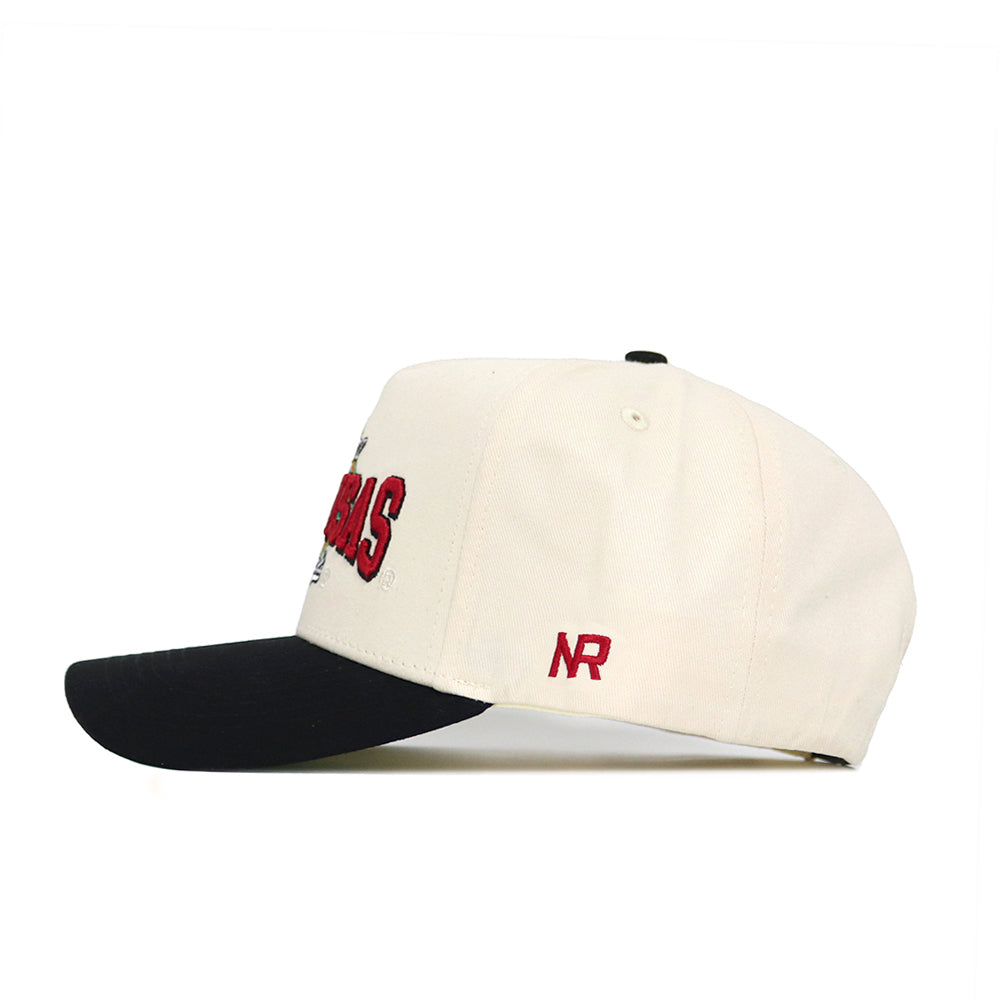 The Arkansas Ballpark Hat by No Rivals is a cream snapback baseball cap with a black brim, red embroidered front letters, and red NR initials on the side, crafted from high-quality cotton. Shown from the side against a white background.