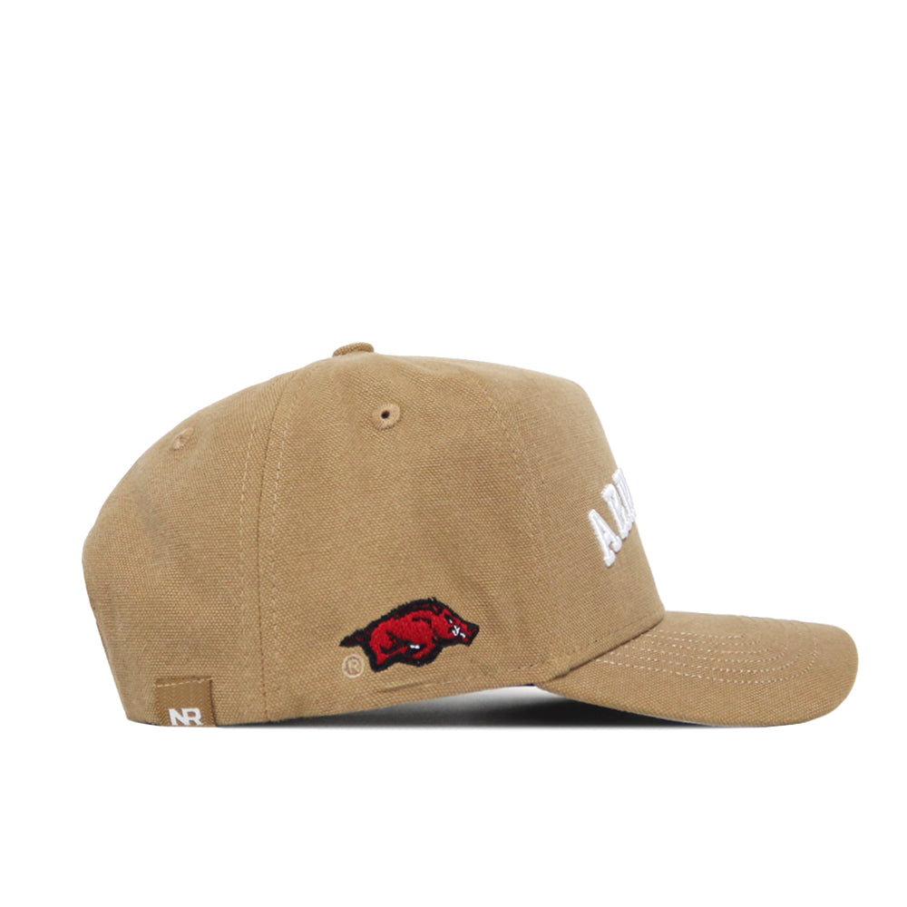 Side view of the Arkansas Rustic Hat—tan cotton-canvas baseball cap with a red hog logo above the left ear, partially visible white front text, ventilation holes, small NR back tag, and a structured snapback fit.