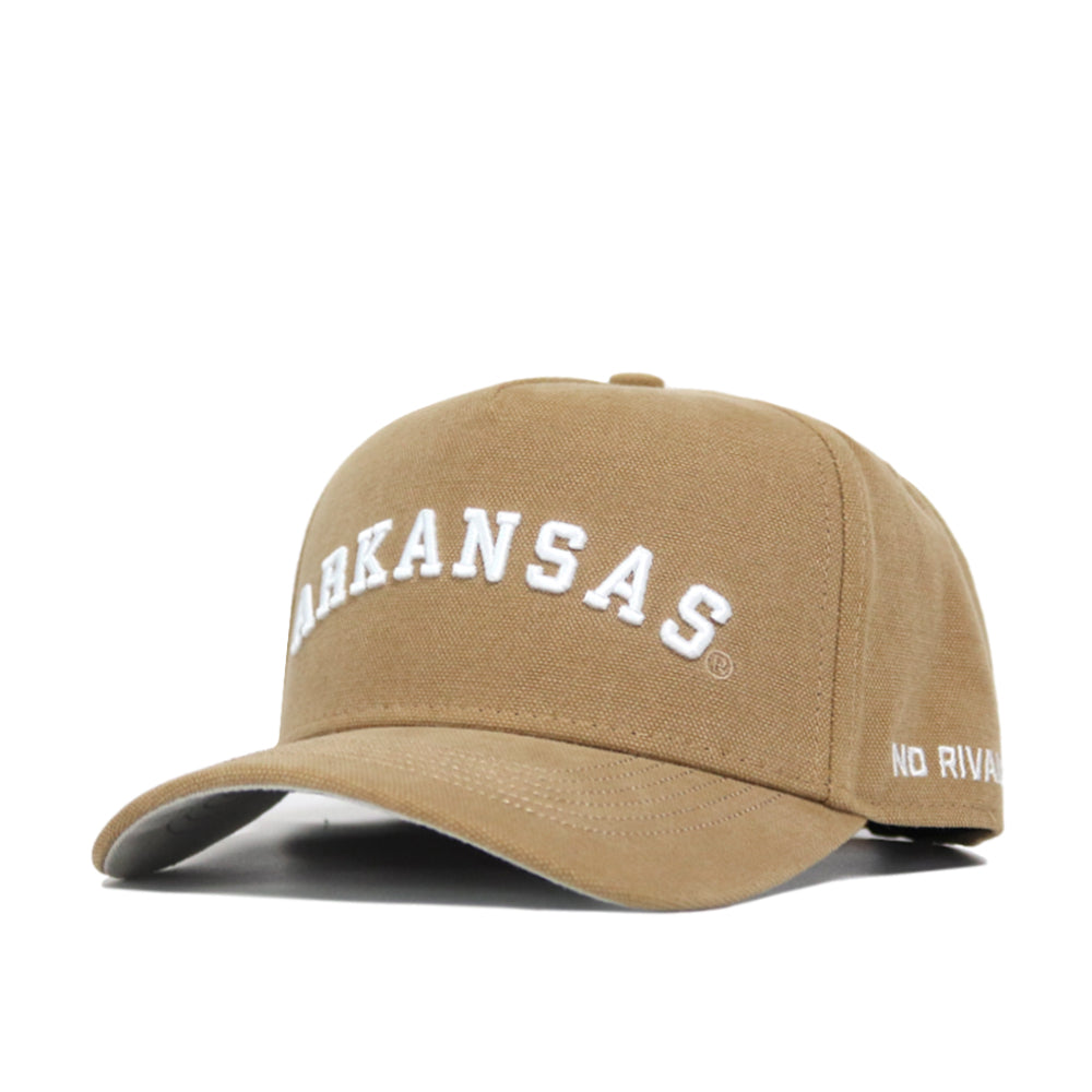 The Arkansas Rustic Hat is a tan cotton-canvas baseball cap with "ARKANSAS" in large white letters on the front and "NO RIVAL" in smaller white letters on the side. It features a structured fit and classic snapback closure.