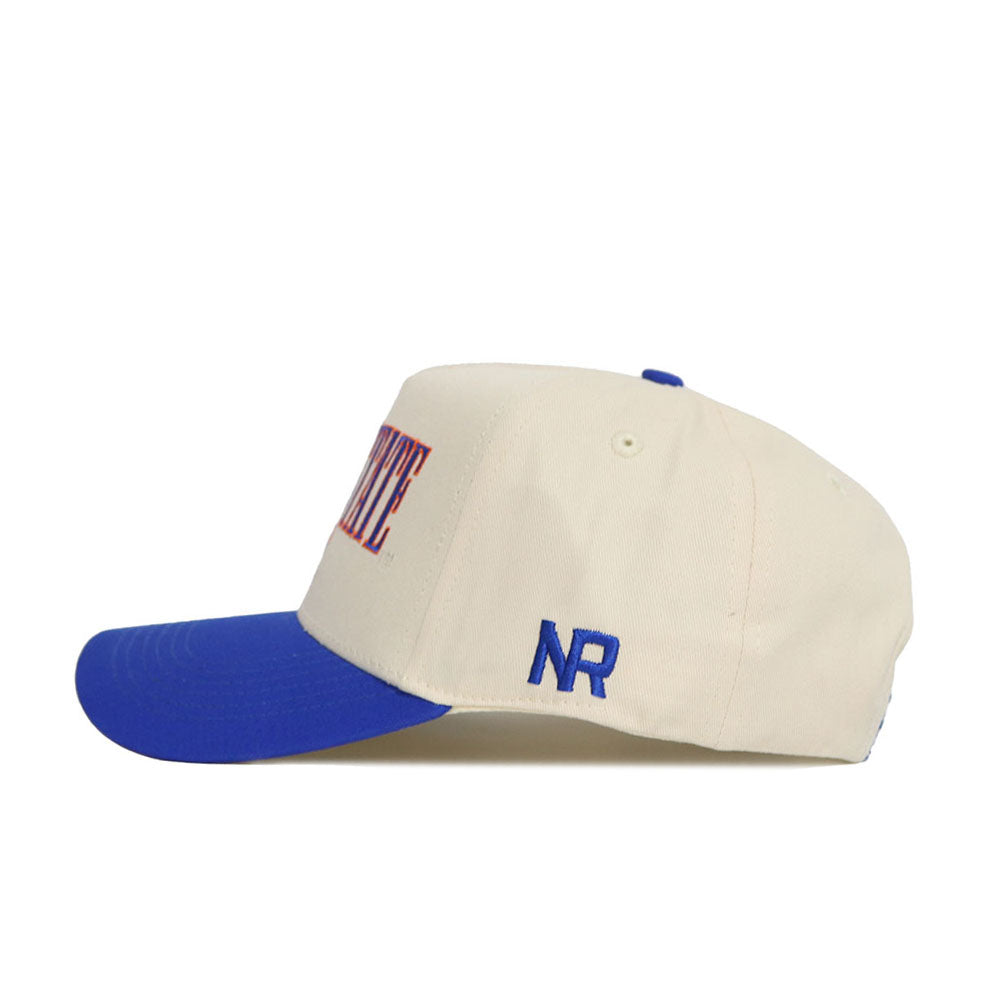 The Boise State Retro Block Hat by No Rivals features a cream snapback design, blue brim, small blue NR on the side, and partially visible red text on the front. Made from high quality cotton for lasting comfort and style.