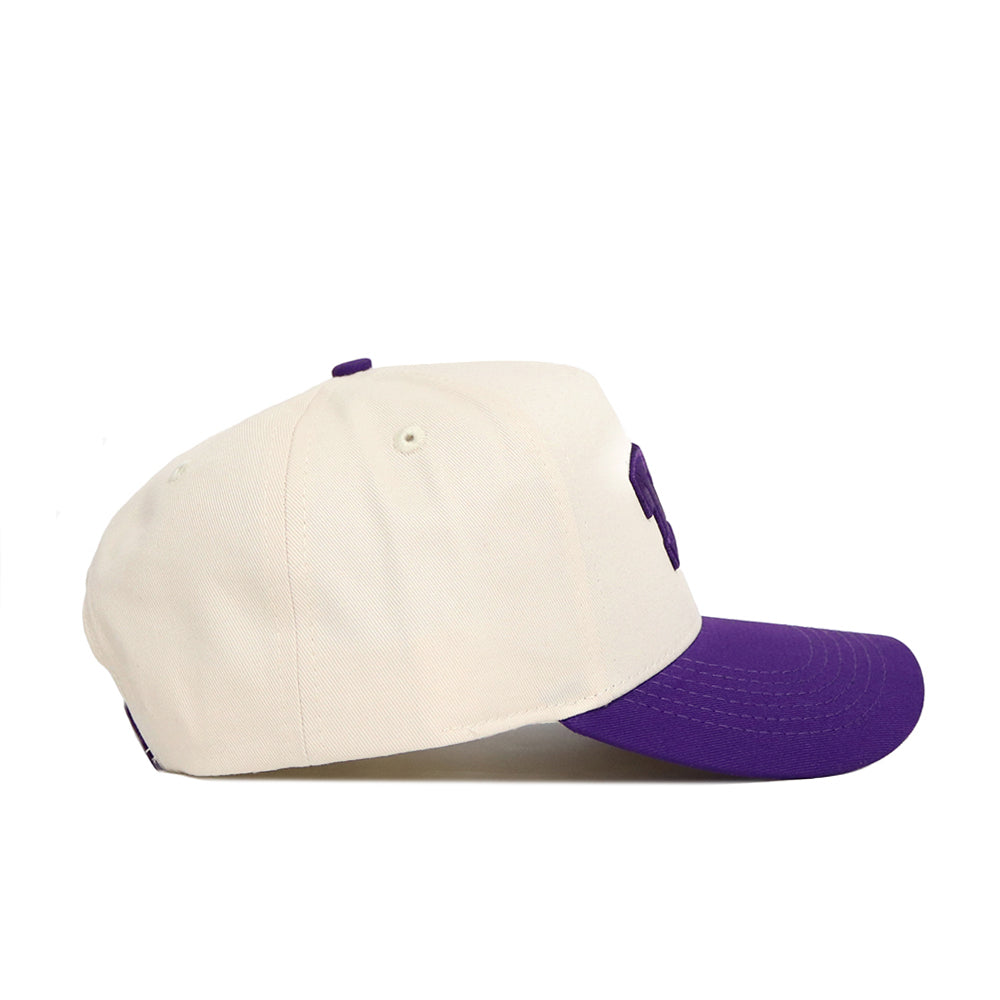 The No Rivals Classic TCU Hat (B2B) features a cream crown and purple brim, shown side view on a white background—ideal for topping off your gameday look.