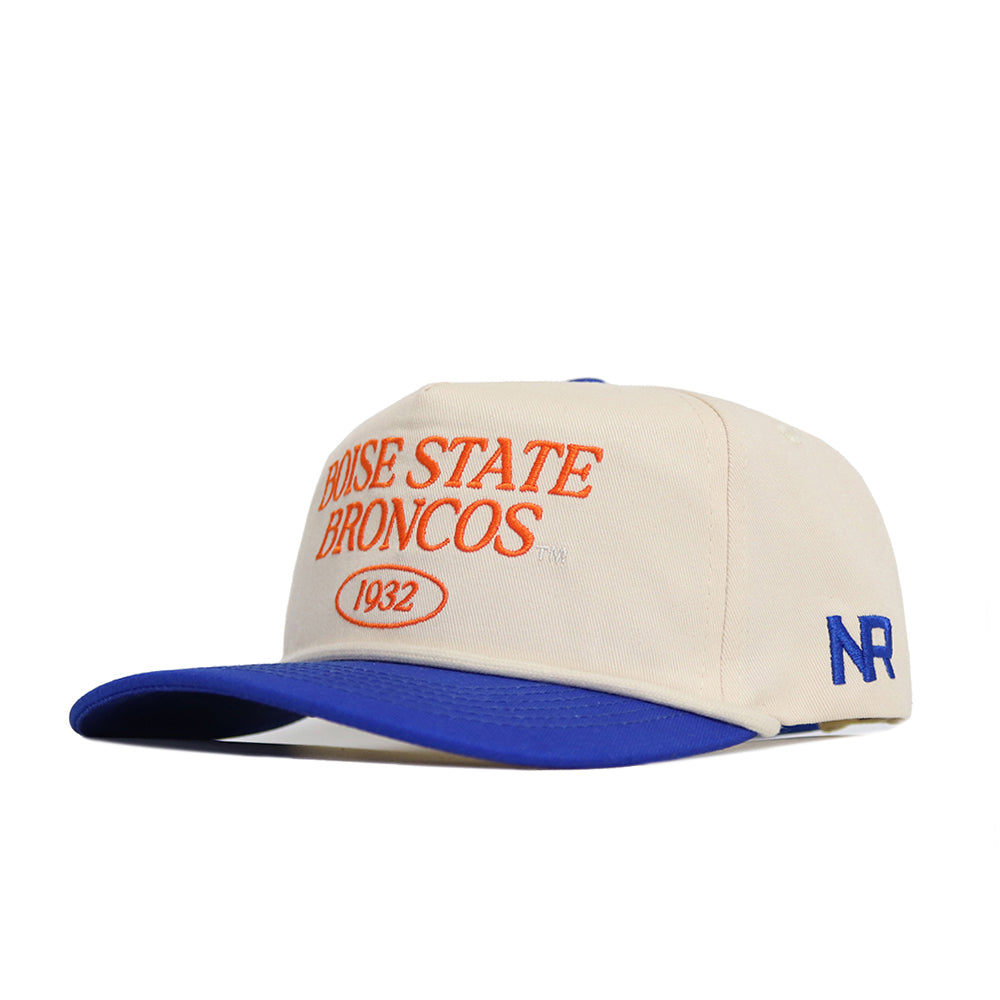 The Boise State Old School Hat (B2B) by No Rivals features a cream cap with "Boise State Broncos 1932" in orange on the front, a blue brim, unstructured fit, snapback closure, and blue NR initials stitched on the side.