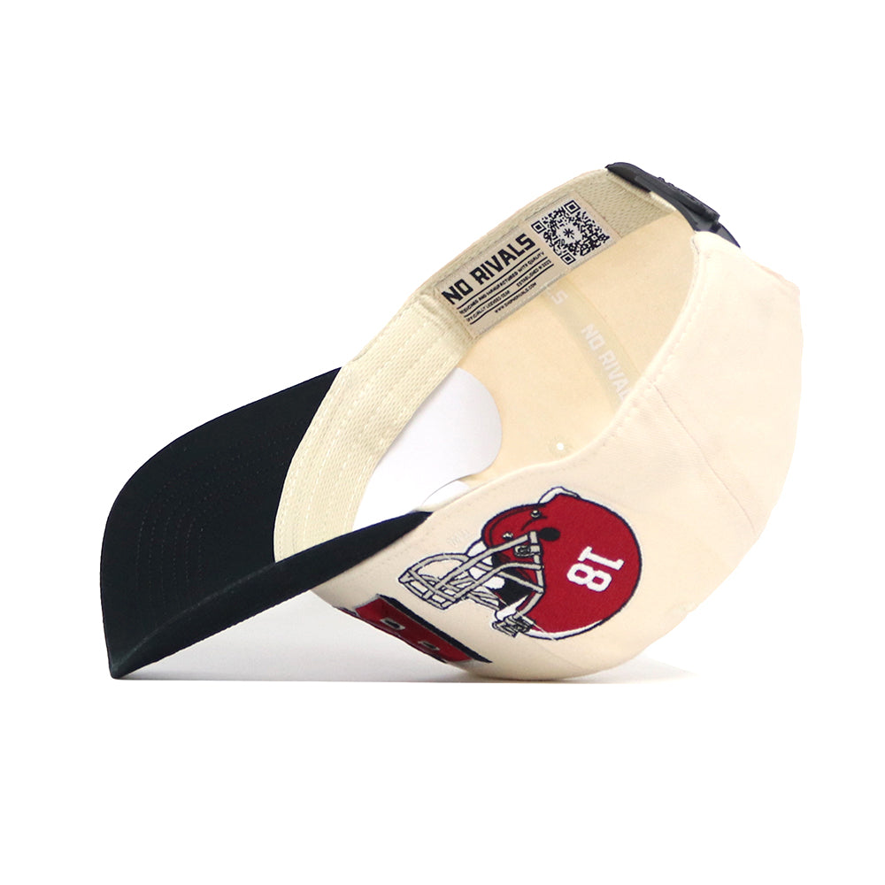 The No Rivals Alabama Alma Mater Hat, shown on its side, displays an interior label and a red football helmet patch with the number 18. This officially licensed snapback features a cream and black design, adjustable strap, and structured fit.