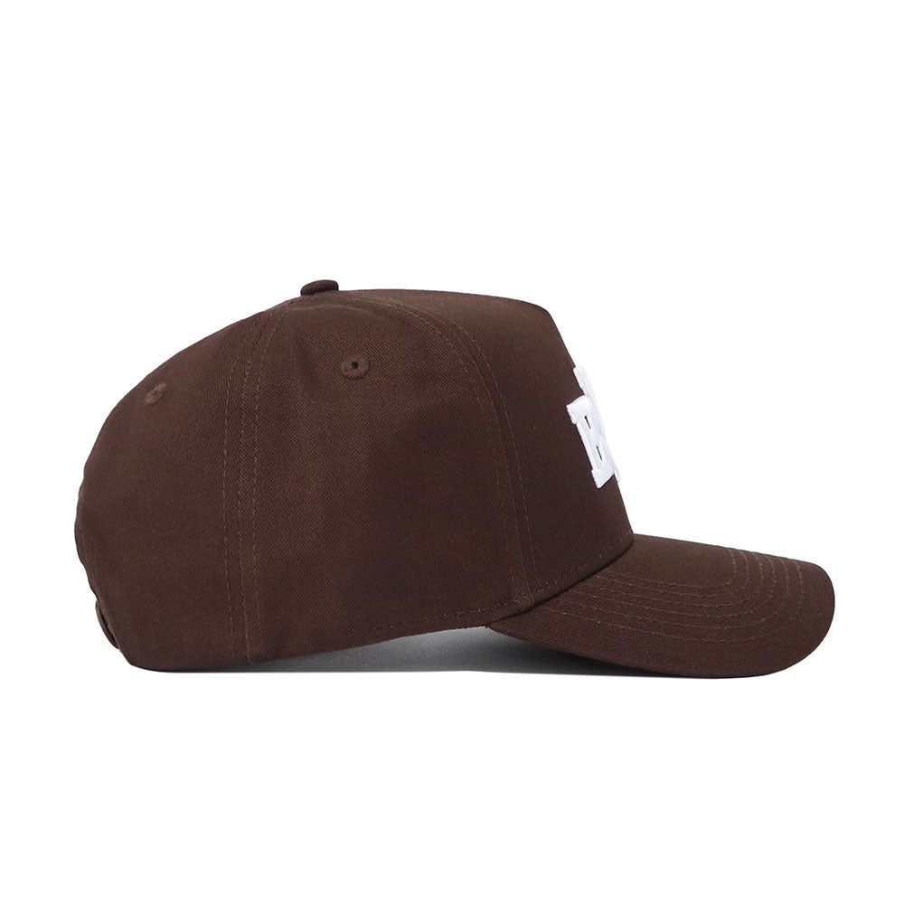 The BYU Americano Hat is shown in side profile, featuring a brown structured snapback design with visible stitching, a curved brim, high-quality cotton construction, and a partially visible raised white embroidered logo.