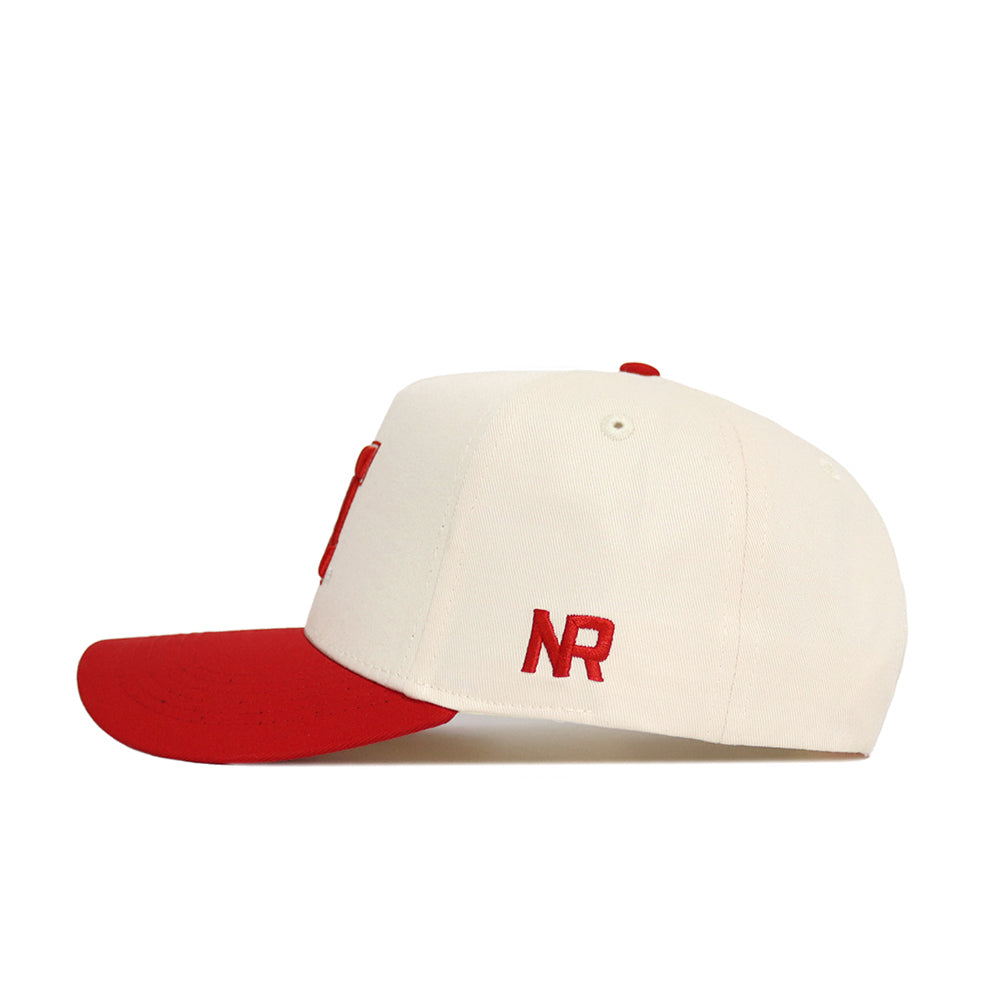 The No Rivals Classic University of Nebraska Hat (B2B) features a white structured cotton design with a red brim and red NR initials embroidered on the side, shown in side profile against a plain white background.