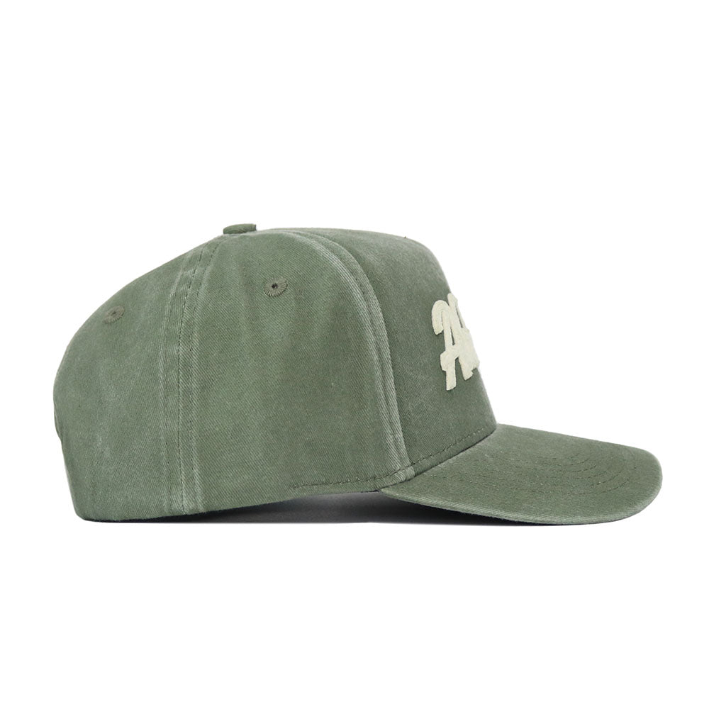 The Alabama Home Turf Hat is a green baseball cap with white embroidered letters, shown from the side. It features a structured fit, curved visor, ventilation eyelets, and an adjustable snap back for a custom fit.