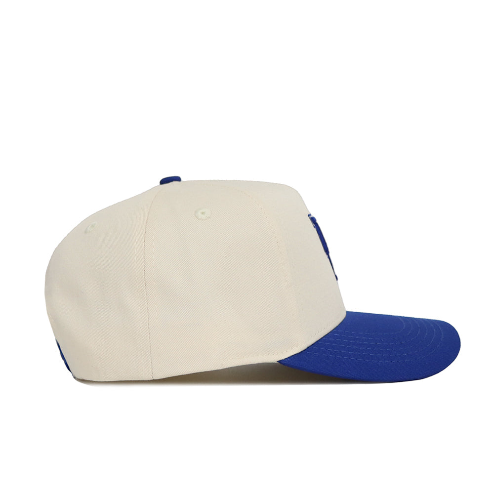 The No Rivals Classic University of Kentucky Hat (B2B) is a cream snapback with a blue brim and structured fit, shown in a side view against a white background.