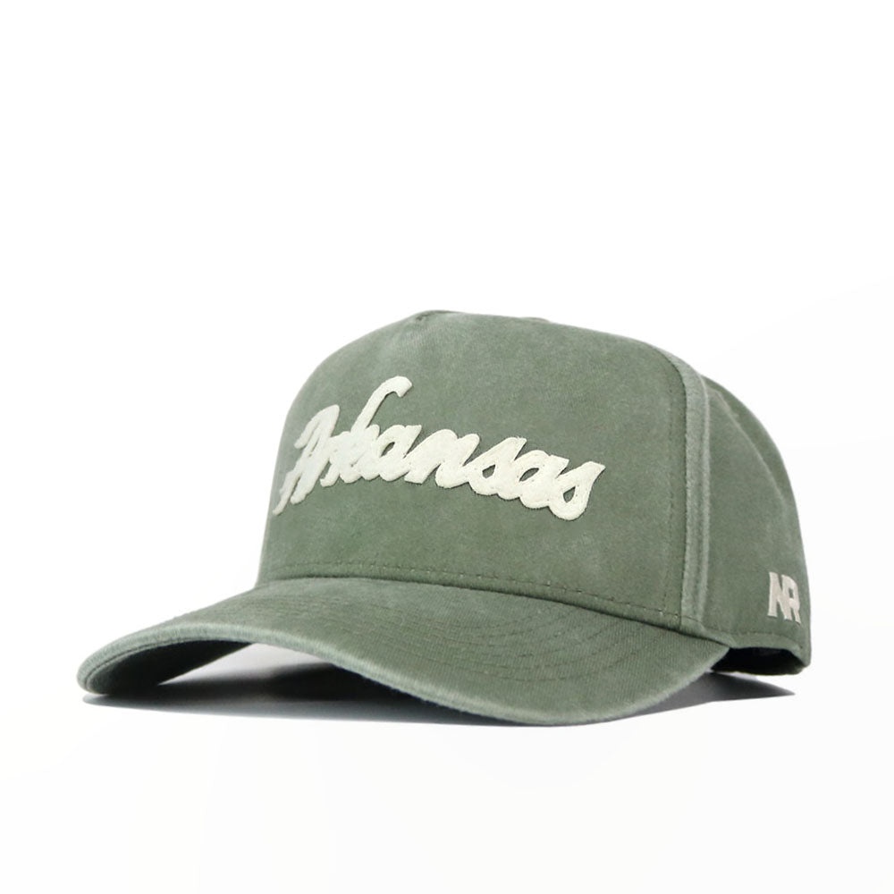 The Arkansas Home Turf Hat is a green washed cotton cap featuring "Arkansas" in white script on the front, "AR" stitched on the side, and an adjustable snapback closure for a comfortable fit.