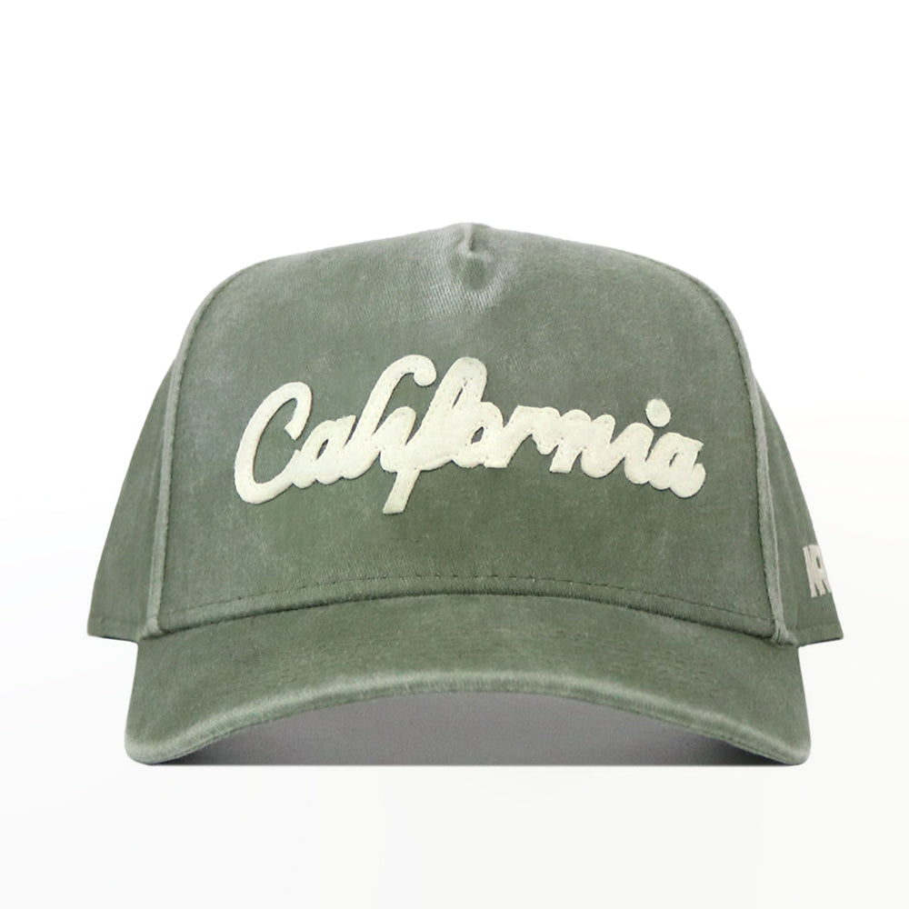 The California Home Turf Hat is a green washed cotton baseball cap with "California" embroidered in white cursive on the front, featuring a classic snapback design.