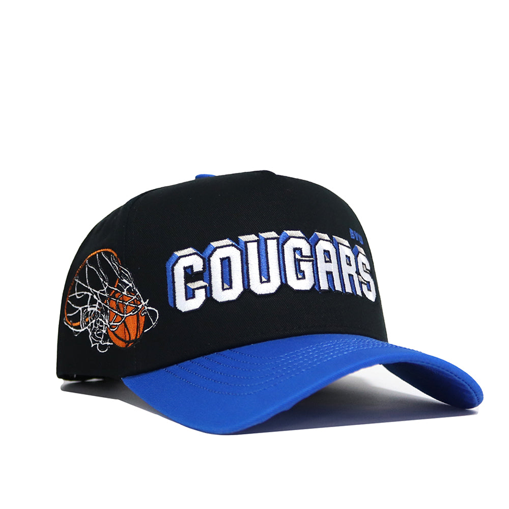 The BYU Courtside Hat is a high-quality cotton snapback in black and blue, featuring "COUGARS" in bold white letters on the front and an embroidered basketball going through a net on the side.