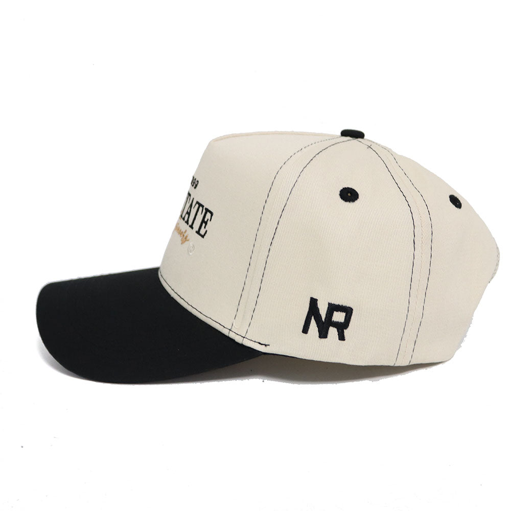 The Appalachian State Vintage Hat by No Rivals is a beige and black snapback with a black front panel and brim, beige body, black stitching, high-quality cotton, and "NR" embroidery on the side for a structured fit.