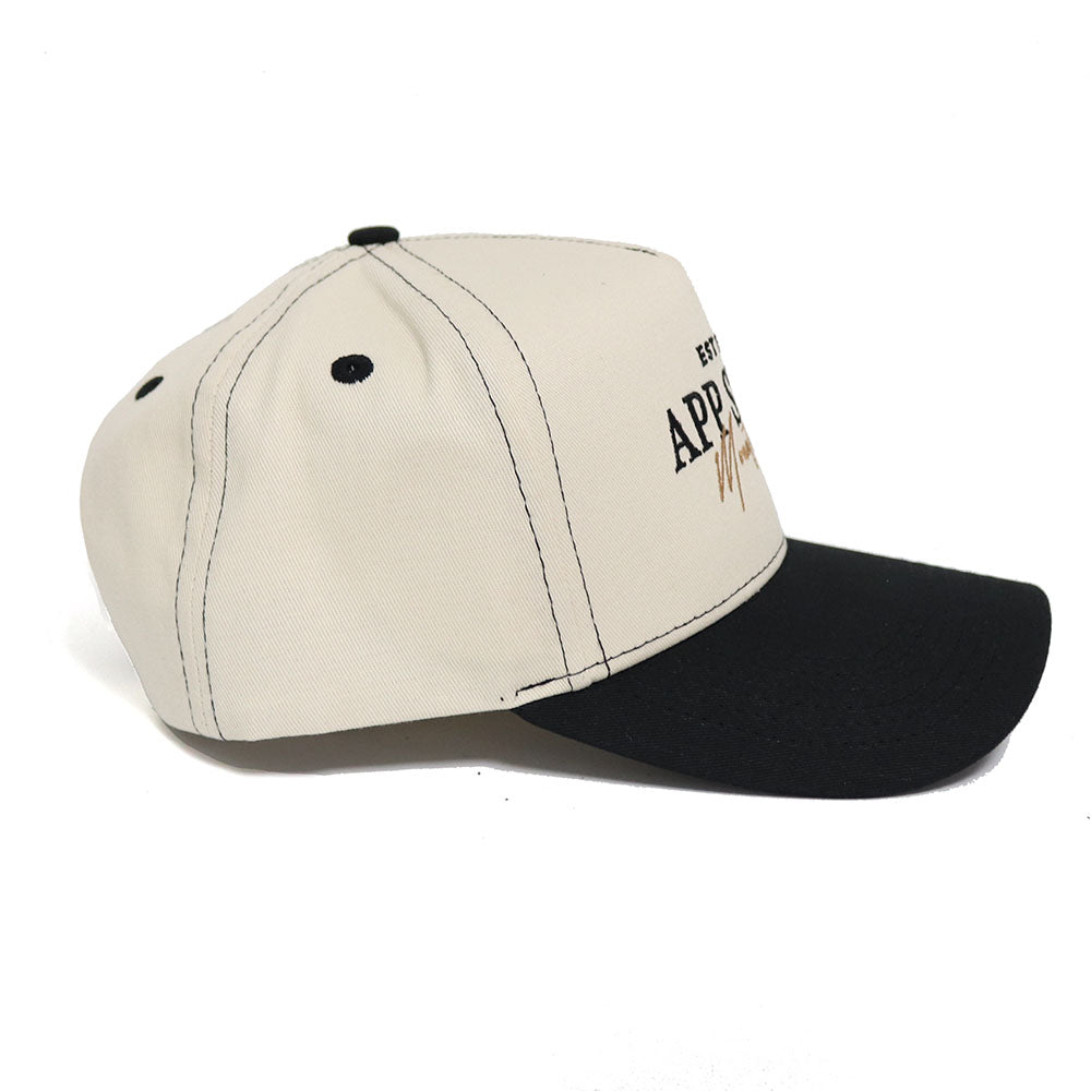 The No Rivals Appalachian State Vintage Hat features a beige and black snapback design with black stitching, ventilation holes, and embroidered text plus a signature in black and tan. Made from high-quality cotton for a stylish, structured fit.