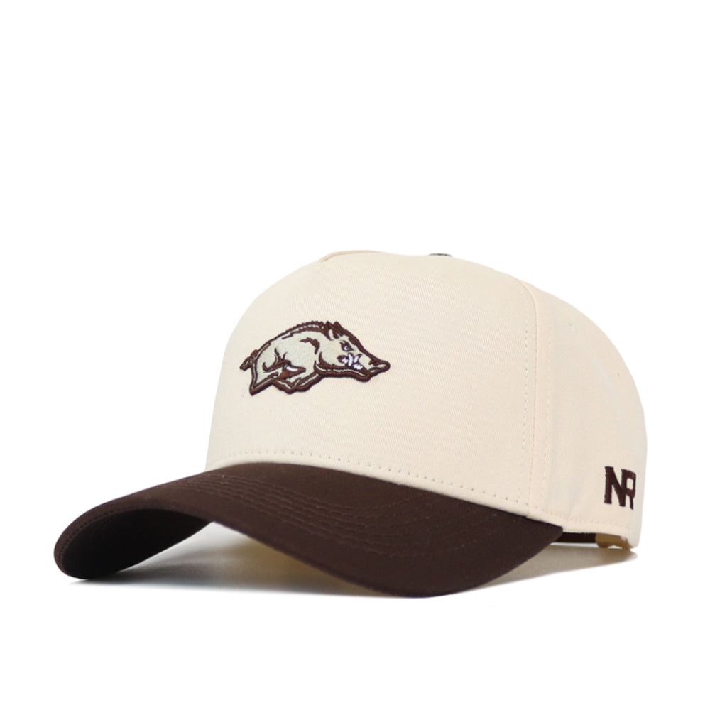The Arkansas Espresso Hat by No Rivals is a cream baseball cap with a brown brim, made from premium cotton. It features an embroidered hog logo on the front and NR initials on the side.