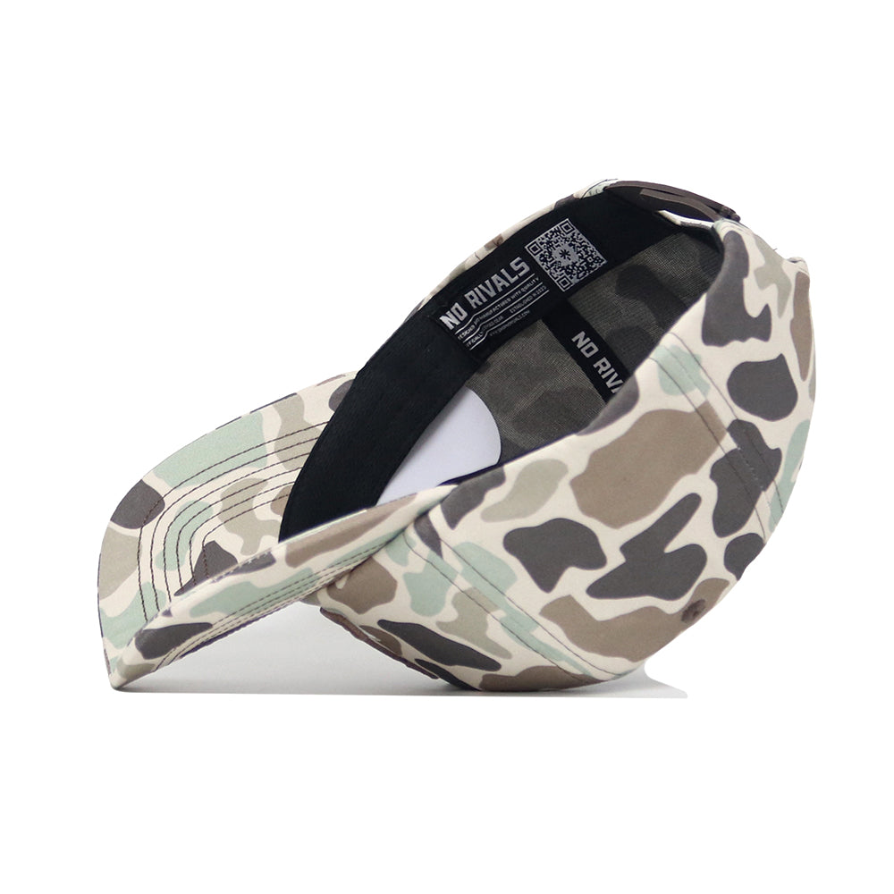 The Arizona Huntsman Hat by No Rivals is a duck camo 5-panel cap in green, brown, and beige with a black sweatband. It’s shown on its side to display the inside label reading NO RIVALS.