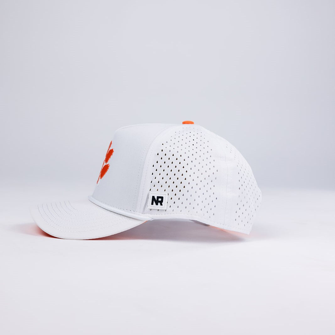 The Clemson Gameday Hat by No Rivals is a white polyester-cotton snapback with small ventilation holes, an orange logo on the front, and a rectangular NR label on the brim. Shown on a plain white background—perfect for your gameday look.