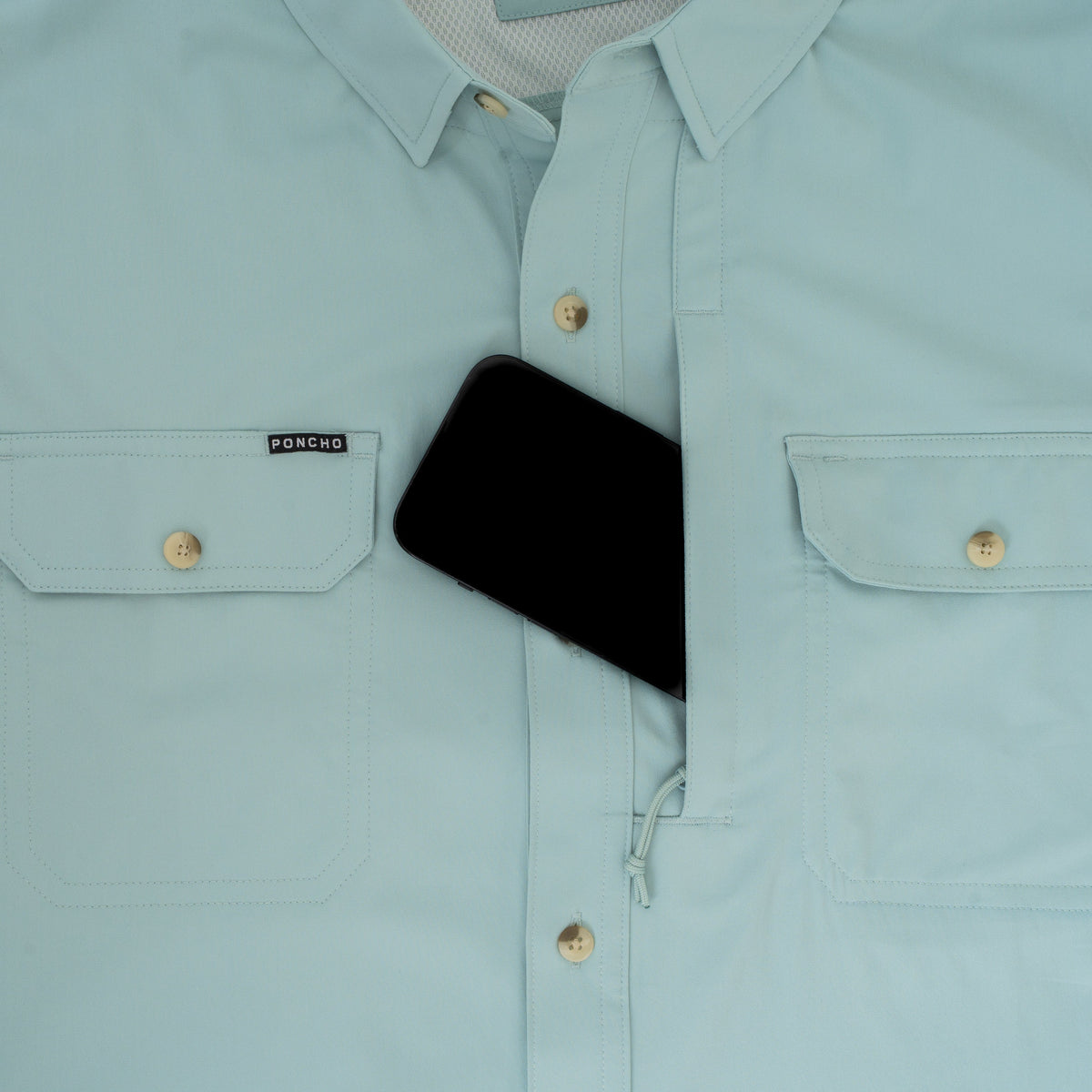 Light blue "The Antilles" outdoor shirt with chest pockets and hidden zippered compartment holding a phone