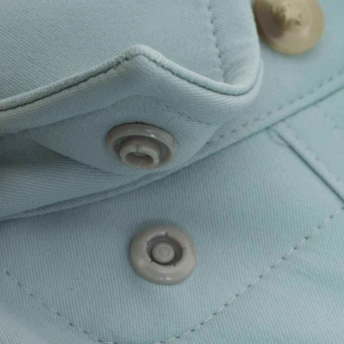 Close-up of light blue fabric with snap buttons on The Antilles outdoor shirt