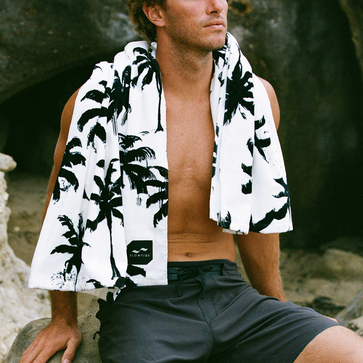 Beach towel, absorbent material, palm tree print draped over shoulders.